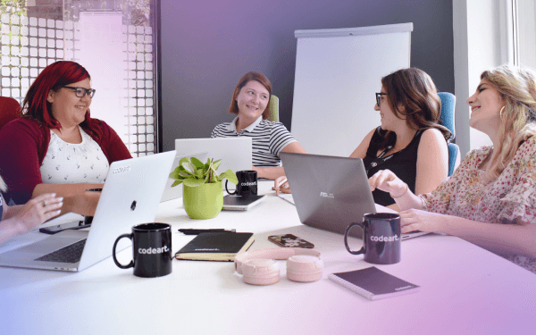 A group of women sitting around a table with laptops, working together on a project